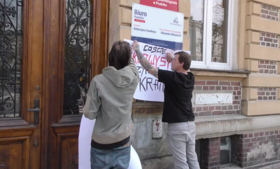 Marek Bień rozwieszający plakat przy wejściu do prudnickiego biura poselskiego PiS [zdj. Internet]