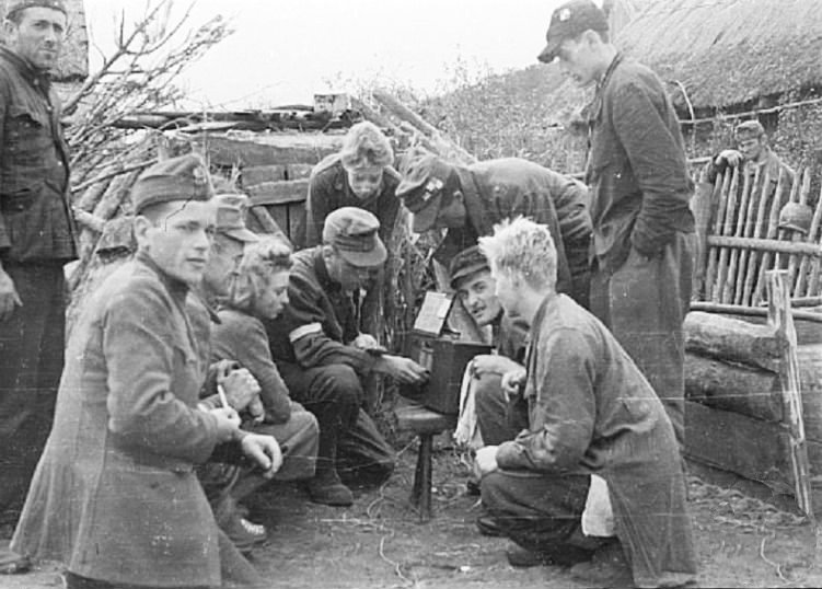 Żołnierze Kompanii Lotniczej Grupy Kampinos słuchają audycji Błyskawicy, we wsi Wiersze, około 15.09.1944 [fot. domena publiczna]