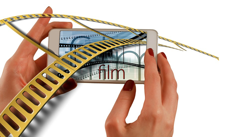 Stwórz film czasu zarazy, weź udział w konkursie "Covideo"! [fot. https://pixabay.com/pl/illustrations/r%C4%99ce-smartphone-kino-strip-film-1167613/]